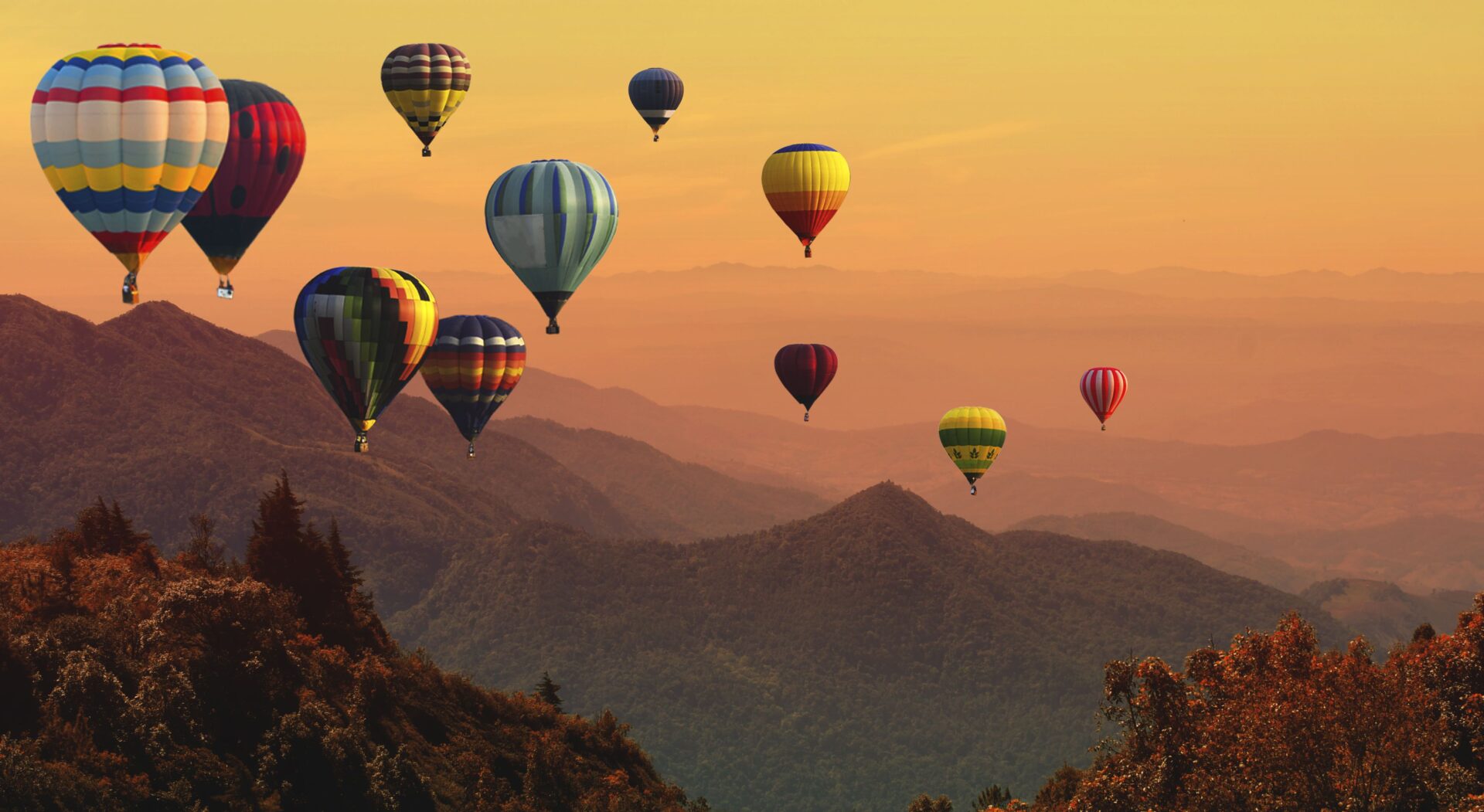 A bunch of hot air balloons flying over the mountains